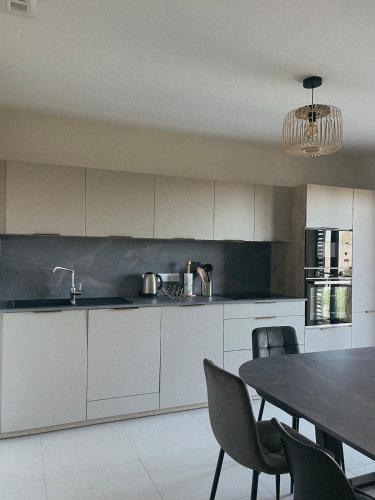 une cuisine avec des armoires blanches et une table avec des chaises dans l'établissement Appartement spacieux 6 personnes sur le vieux port, à Porto-Vecchio