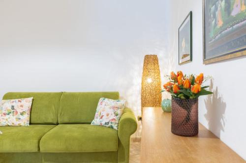 a living room with a green couch and a vase of flowers at Maria House con giardino privato in Olbia