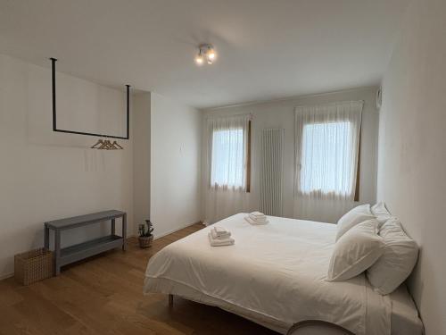 Un dormitorio con una gran cama blanca y dos ventanas. en Casa Polimar Quattro, en Asolo