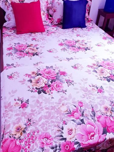a bed with a floral bedspread with pink flowers on it at Meubles & Meublés - Le Boisé - Studio meublé Yaoundé Ekié in Yaoundé