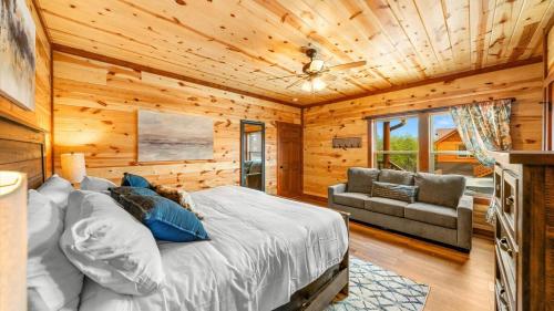 Dormitorio en cabaña de madera con cama y sofá en Luxe Memory Maker View Indoor Pool Games Sleeps 20, en Sevierville