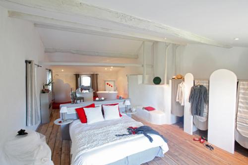 une chambre avec un grand lit blanc avec des oreillers rouges dans l'établissement Luxueux Mas de Village 18ème siècle, à Massannes