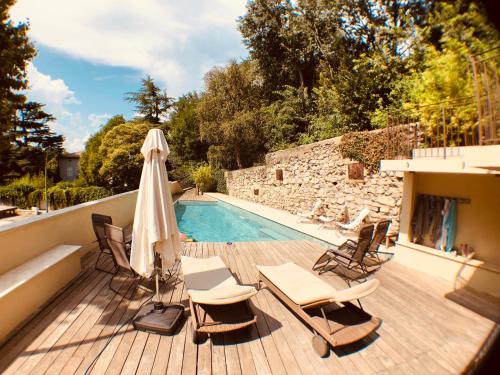 une terrasse avec des chaises et un parasol, ainsi qu'une piscine dans l'établissement Luxueux Mas de Village 18ème siècle, à Massannes