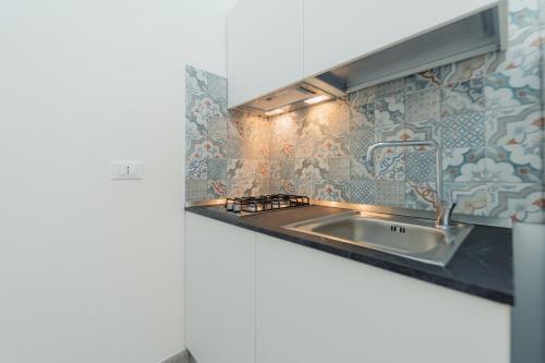 a kitchen with a sink and a tile wall at La dimora del cavatore in Favignana