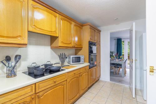 a kitchen with wooden cabinets and a counter top at Newly refurbed, 5BR, Sleeps 12 in Northampton