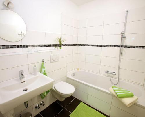 a bathroom with a sink and a toilet and a bath tub at Hotel Olive Inn in Aschaffenburg