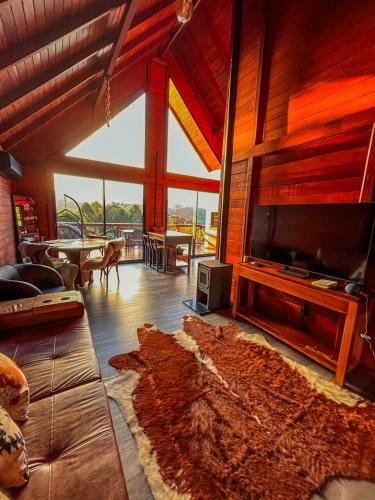 a living room with a couch and a tv at Rancho Texel Chalé de Luxo in Rancho Queimado