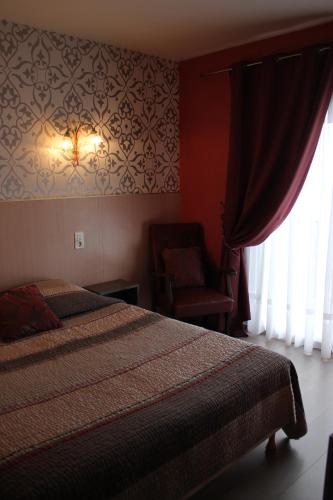 a bedroom with a bed and a chair next to a window at Hôtel Restaurant le Panorama in Évian-les-Bains