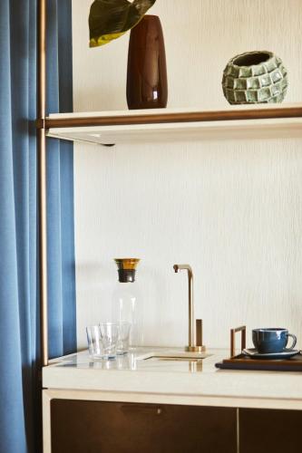 a kitchen counter with a sink and glasses on a shelf at Hotel Arts Barcelona in Barcelona