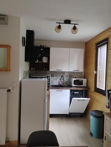 Il comprend une cuisine équipée d'appareils électroménagers blancs et d'un réfrigérateur blanc. dans l'établissement studio familial 4 couchages, à Arâches-la-Frasse