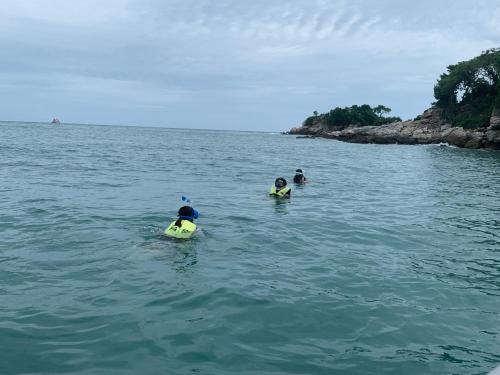 three people are swimming in the water in the ocean at Koh Samed Lung Dam Hutbeach in Ao Phutsa