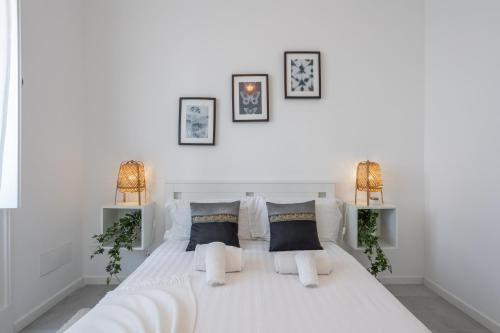 een witte slaapkamer met een groot wit bed met 2 lampen bij Charming and Cozy beach apartment in Estoril