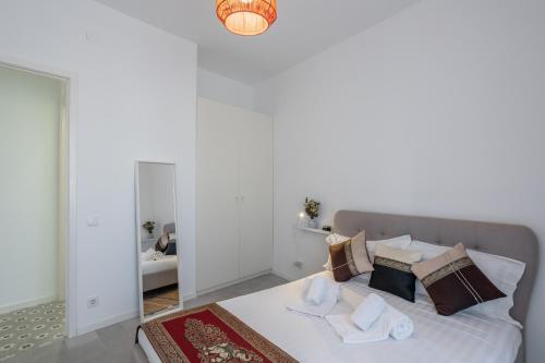 een slaapkamer met een groot wit bed met kussens bij Charming and Cozy beach apartment in Estoril
