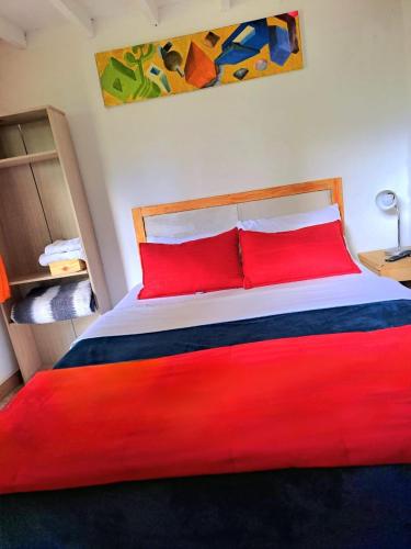a bed with red pillows in a room at Hotel Marrokos Aeropuerto José María Córdova in Rionegro