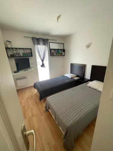 - une chambre avec 2 lits et une télévision dans l'établissement Appartement à Soulac-sur-mer, Résidence Villa Marine, à Soulac-sur-Mer
