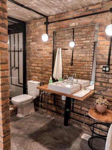 a brick bathroom with a sink and a toilet at Monte Sião Château in Urubici