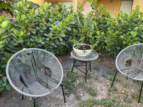 three chairs and a table in front of a bush at 2 Bedroom Apartment Free Reserved Parking in Miami