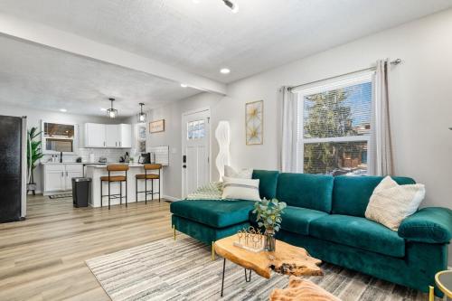 a living room with a green couch and a kitchen at Game Room Retreat with Firepit and Gym, Sleeps 12 in Indianapolis