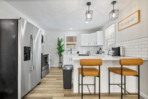 a kitchen with two bar stools and a refrigerator at Game Room Retreat with Firepit and Gym, Sleeps 12 in Indianapolis