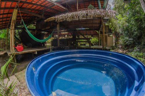 a blue pool in front of a house with a hammock at Suíte Curuaçu in Santarém