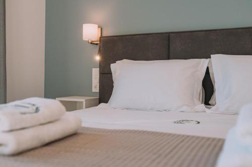 a bedroom with a bed with white sheets and pillows at Thea Apartment near the Agkali - Ayia Anna beach in Evia in Kría Vrísi