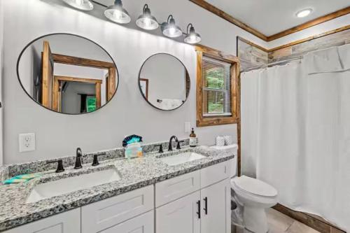 a bathroom with two sinks and a toilet and a mirror at Smoky Mtns Private w/Hot Tub, Game Room, Pets Free in Sevierville