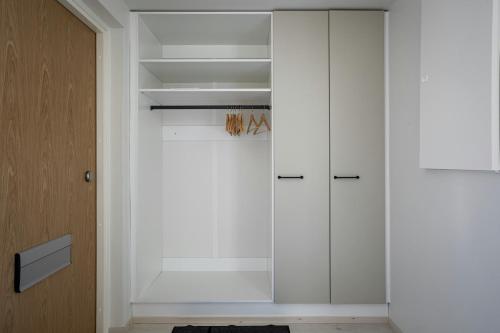 a walk in closet with white cabinets and a door at Convenient Apartment for 5 with Sauna in Kirkkonummi