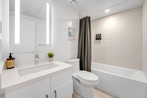 a white bathroom with a toilet and a sink at Cozy Condo Near Restaurant TTC in Toronto