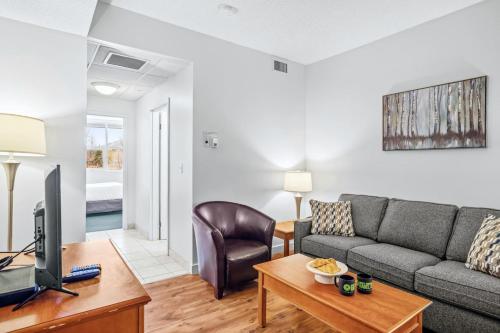 a living room with a couch and a tv at Serene 1BR Retreat Mtn Views, Pool, and Hot Tub in Canmore