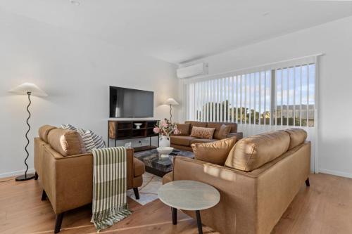 a living room with two couches and a table at Premium Sunset Townhouse with 6 Aircons near Airport in Auckland