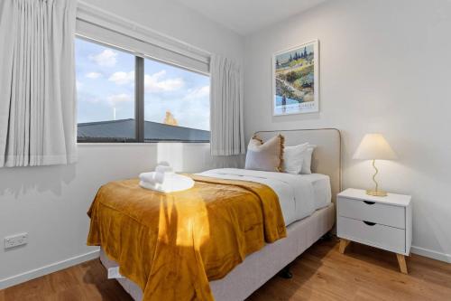 a white bedroom with a bed with a yellow blanket at Premium Sunset Townhouse with 6 Aircons near Airport in Auckland