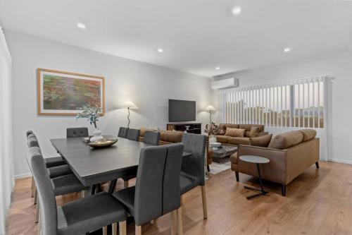 a dining room and living room with a table and chairs at Premium Sunset Townhouse with 6 Aircons near Airport in Auckland