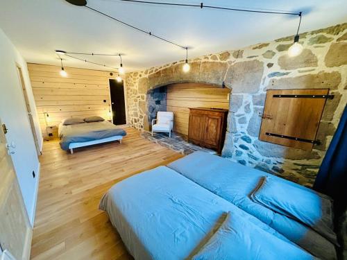 een slaapkamer met een bed en een stenen muur bij Maison cosy avec sauna en montagne in Saint-Jacques-des-Blats