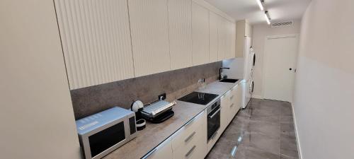 a kitchen with white cabinets and a sink and a microwave at Sol Del Mar in Benicarló