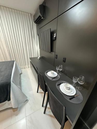 a dining table with two plates and wine glasses on it at Compact Time apto 406 Lindo Flat in João Pessoa