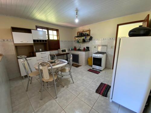 a kitchen with a table and a white refrigerator at LUMIAR TEMPORADA CASA VILAREJO COM WI-fi TV A CABO PERTINHO DO POÇO FEIO E DA PRAÇA CENTRAL in Lumiar