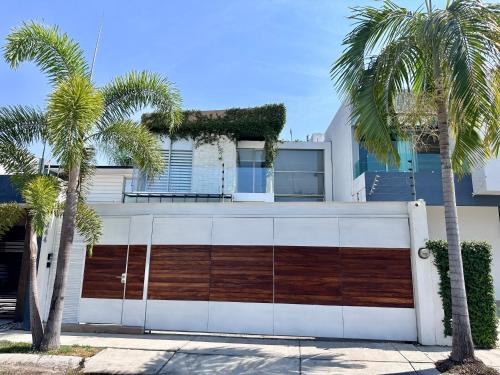 a white house with palm trees in front of it at Beautiful House with Climate Pool and Jacuzzi in Colima