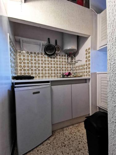 une petite cuisine avec des armoires blanches et une cuisinière dans l'établissement Résidence Les Arcades 2 - STUDIO MEZZANINE 4 PERSONNES 4 couchages LE BARCARÈS. Réf: 9ARC2_136 MAE-8493, au Barcarès