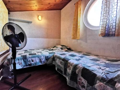 Cette chambre comprend un lit, un ventilateur et une fenêtre. dans l'établissement Résidence Les Arcades 2 - STUDIO MEZZANINE 4 PERSONNES 4 couchages LE BARCARÈS. Réf: 9ARC2_136 MAE-8493, au Barcarès
