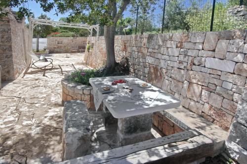 a stone wall with a table in front of a tree at Trullo San Giovanni in Castellana Grotte