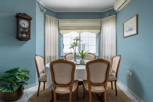 a dining room with a table and chairs and a clock at Serenity Guesthouse in Sitia