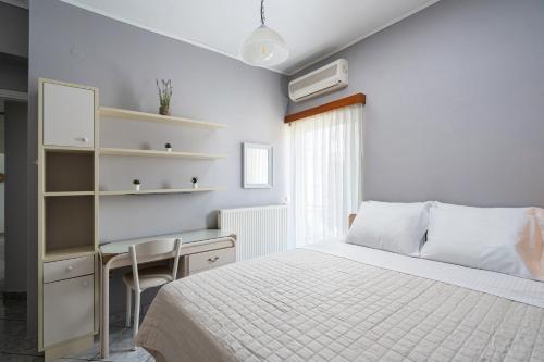 a white bedroom with a bed and a desk at Serenity Guesthouse in Sitia