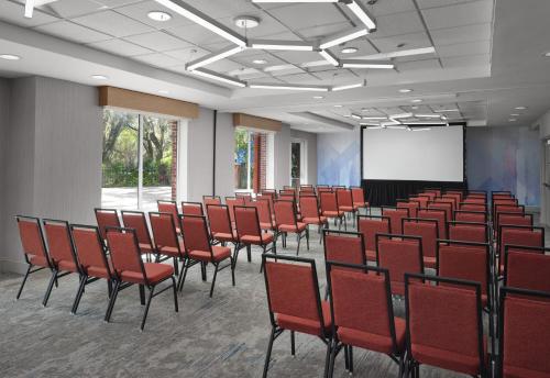 a conference room with red chairs and a screen at Hilton Garden Inn Tampa East Brandon in Tampa