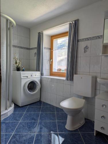 a bathroom with a washing machine and a toilet at Casa Letizia in Brigels