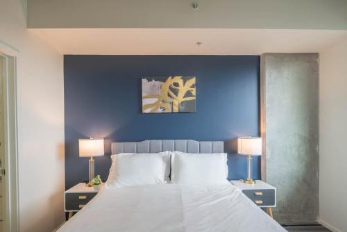 a bedroom with a blue wall and a bed with two lamps at Lovely 1BD - Central Downtown - Gym, Pool, Parking in Phoenix