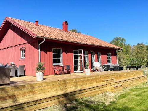 a red house with a wooden deck in front of it at 5 person holiday home in KLÖVEDAL-By Traum in Klövedal
