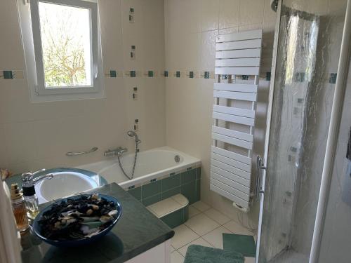 a bathroom with a sink and a bath tub at Maison spacieuse et lumineuse à seulement 1 minute de la mer in Rosnoën