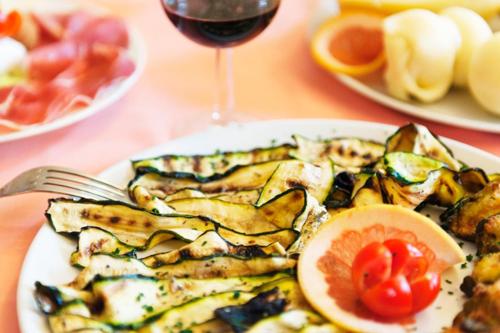 a plate of food with a grapefruit and a glass of wine at Le Coccole in Guardiaregia
