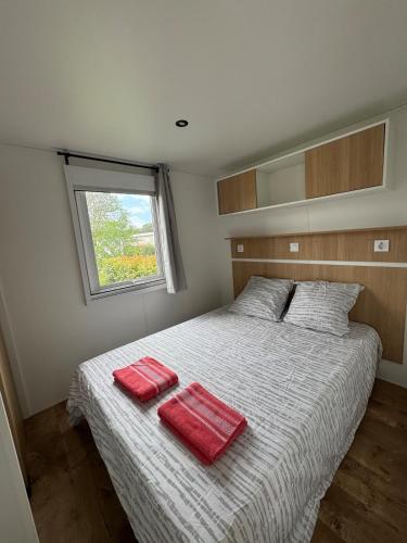 - une chambre avec 2 serviettes rouges sur un lit dans l'établissement Mobile Home 146, 5 pers Camping Siblu 4 étoiles le Lac des Reves, à Lattes