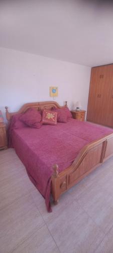 a bedroom with a large wooden bed with purple sheets at Jordi's Flat close to the Beach in L'Estartit